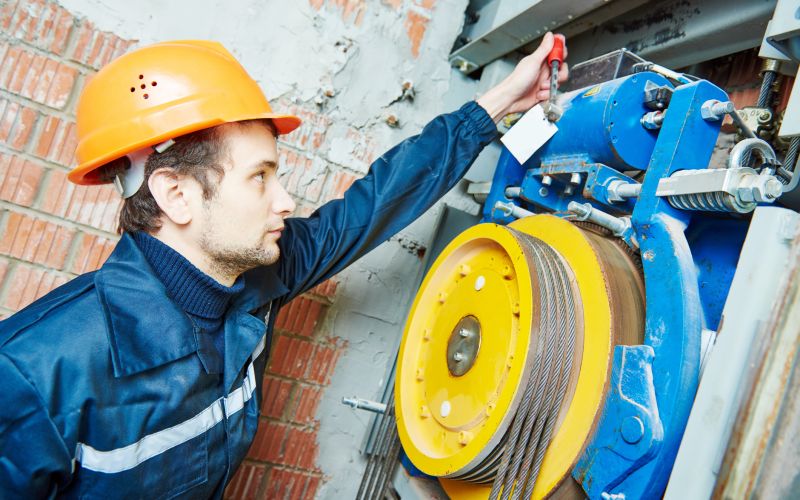machinist worker adjusting elevator mechanism of lift
